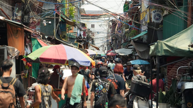 A crowded market street in Manila under umbrellas and tangled wires