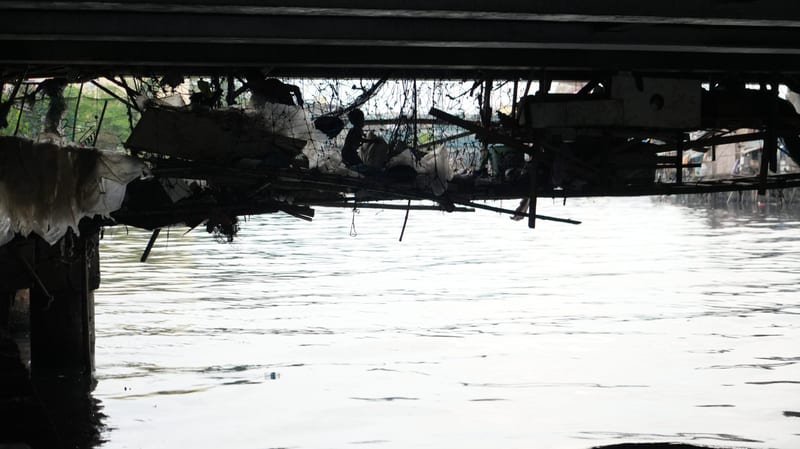 The dark underside of a bridge above the river, light on the water