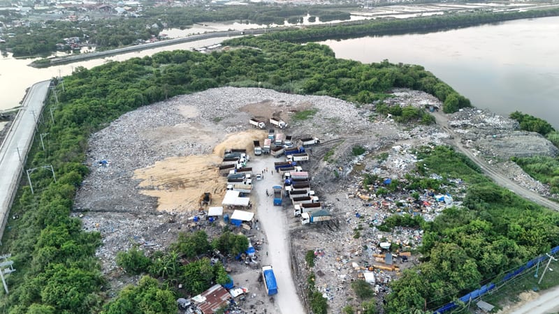 From the air, a landfill on the coast with trucks parked in its centre and the sea beyond