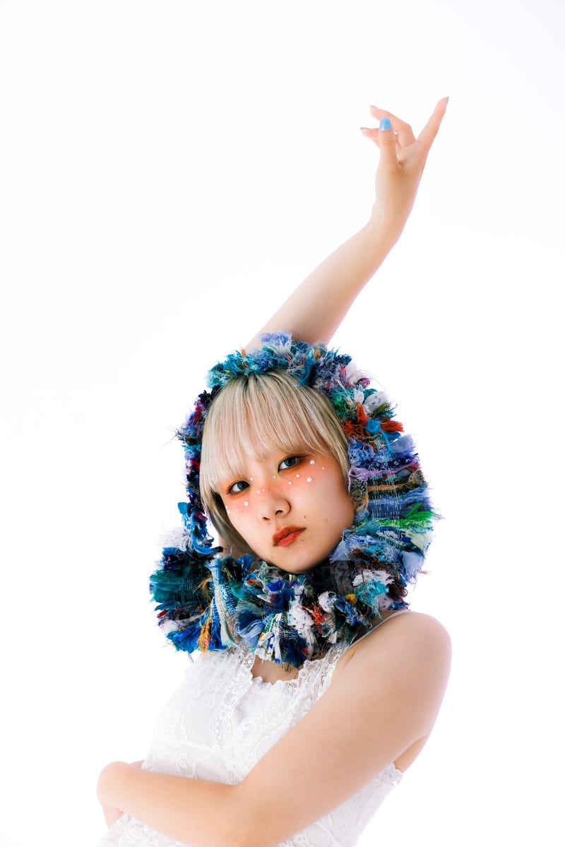 In a knitted hood, a person reaches one arm high above their head